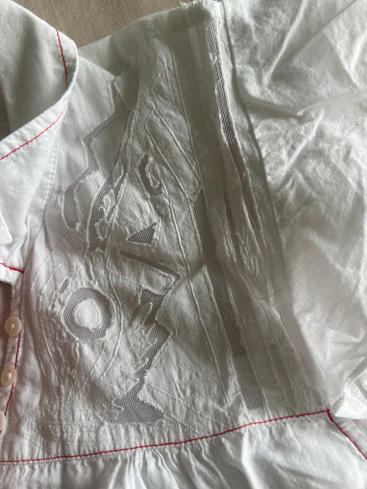 Camisa blanca con transparencias y detalles rojos